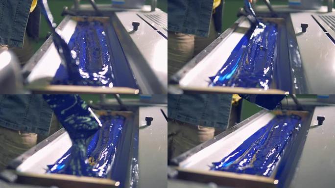 一名员工正在打印托盘中的蓝色油漆上传递刷子