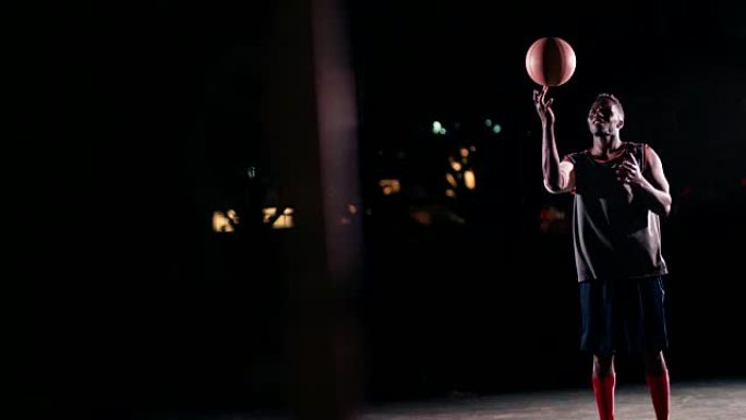 篮球运动员在夜间在球场上用手指旋转球