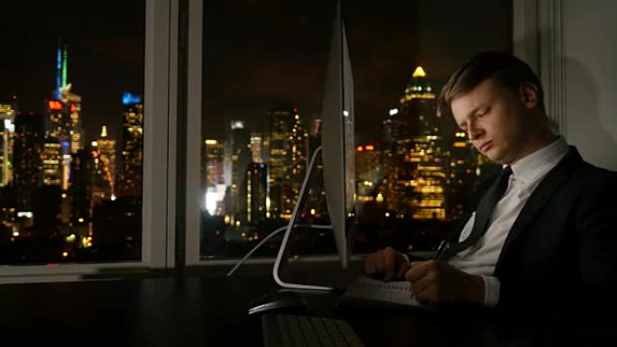 年轻成功的商人在现代办公室工作，晚上在电脑上分析图表。商务电话交谈。