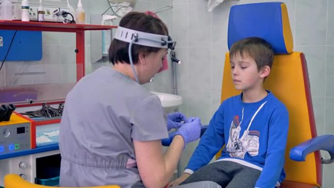 医生用棉签检查儿童患者的鼻子。