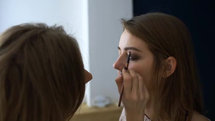 化妆师在重要事件发生前为女孩做漂亮的眼睛化妆