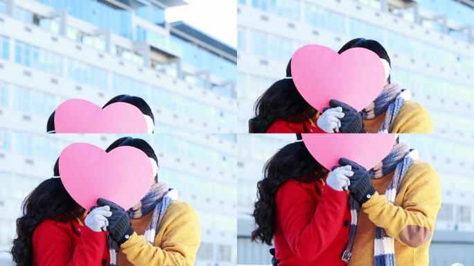 亚洲夫妇在粉红色的心脏下遮住脸
