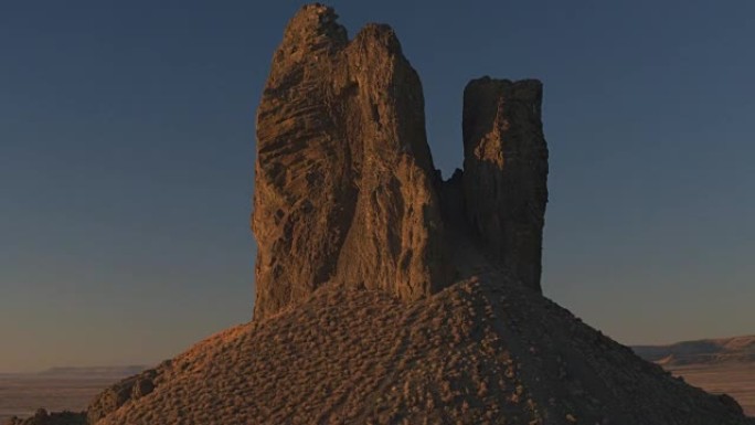 空中: 日出时在火山沙漠中的岩石野猪Tusk地标上飞行