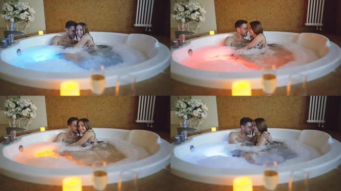 年轻的大胡子男人和他迷人的女友在浴缸里聊天，拥抱和大笑。浪漫关系、健康和幸福的人的概念。