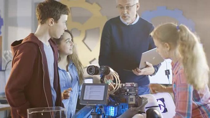老师和他的学生在带有LED照明的可编程机器人上进行学校科学课项目。