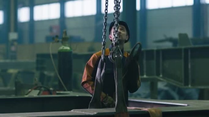 一家工厂的重工业工人正在操作带遥控器的起重机。