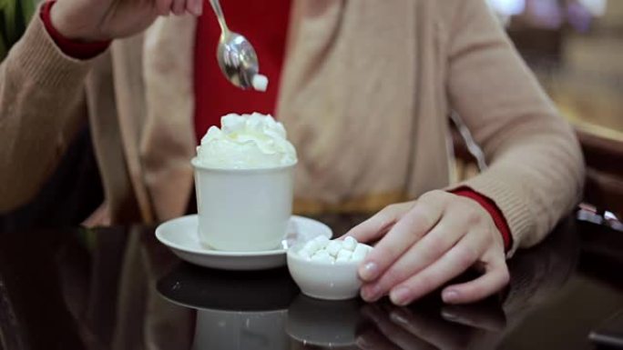 女人在咖啡中加入棉花糖加奶油