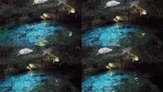 年轻女子游泳并探索绿松石cenote池的秘密黑社会