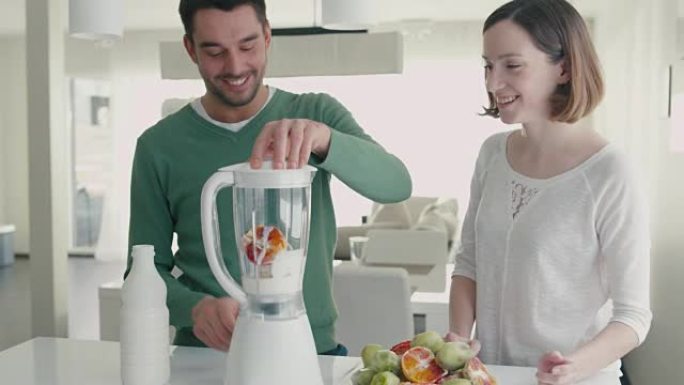 幸福浪漫的情侣正在家里厨房的搅拌机里做冰沙。