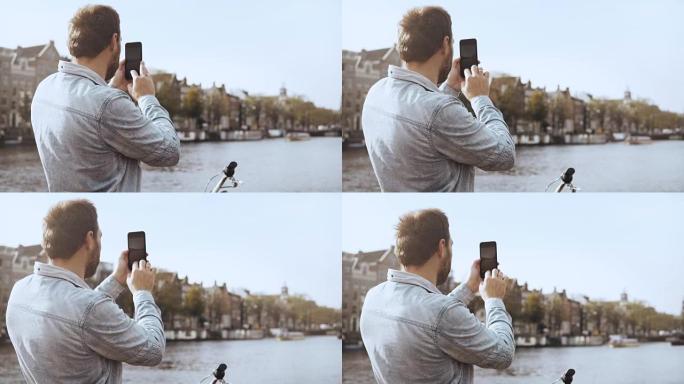 4k欧洲旅游男子在桥上拍照。智能手机摄影。带自行车的成人休闲旅行者