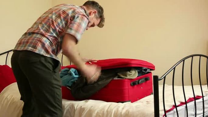 男人在收拾他的行李箱——很难合上！
