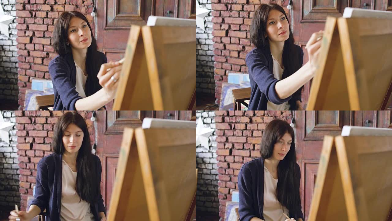年轻女性艺术家在画架画布上用水彩颜料和画笔绘制画图