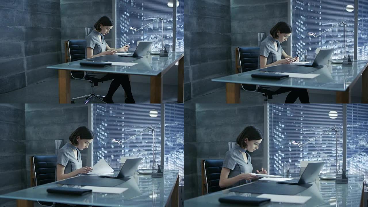 成功的年轻女子坐在办公桌前的私人办公室里，在笔记本电脑上工作，签署重要文件。她的办公室以极简主义风格