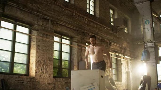运动赤膊壮汉在硬核健身房大力拳击跳跃。男人是汗水从激烈的锻炼/锻炼，健身房是在风景如画的废弃工厂位置