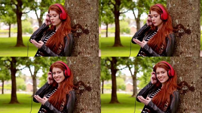 漂亮的红发女郎在公园听音乐