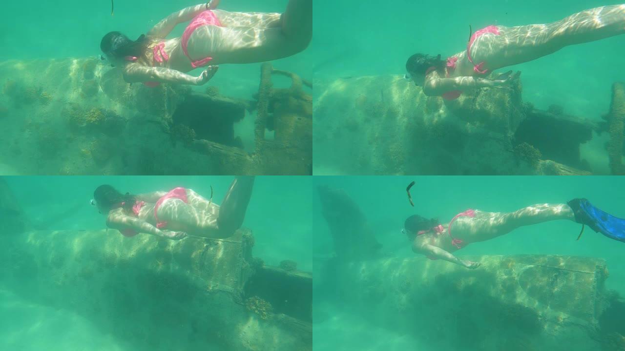水下: 年轻的女旅行者在海洋中潜水时探索沉没的飞机
