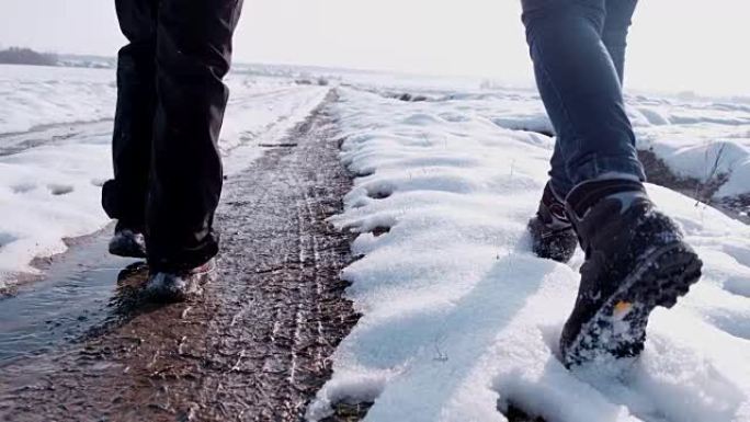 穿着靴子的徒步旅行者走在白雪皑皑的冬季道路上，超级慢动作