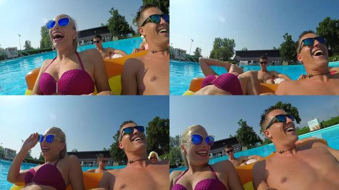 自拍照: 年轻夫妇在游泳池中的充气漂浮物上大笑并玩乐