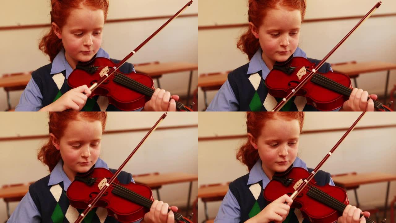 可爱的小学生在教室里拉小提琴