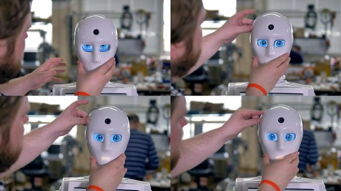 一位工程师在机器人脸上戴上白色面具。