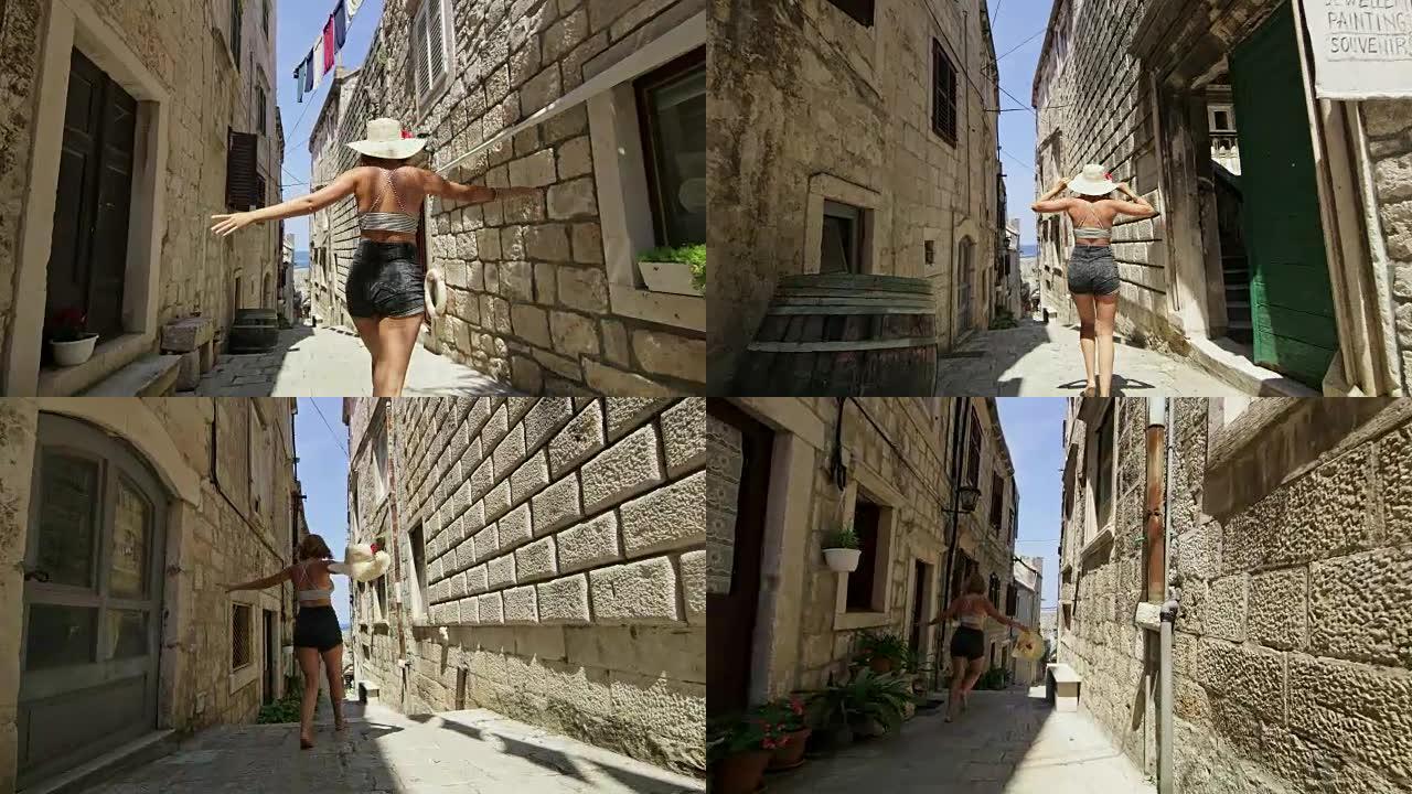 女士无忧无虑，顽皮的女游客在克罗地亚科尔库拉岛的阳光明媚的小巷中奔跑和跳跃