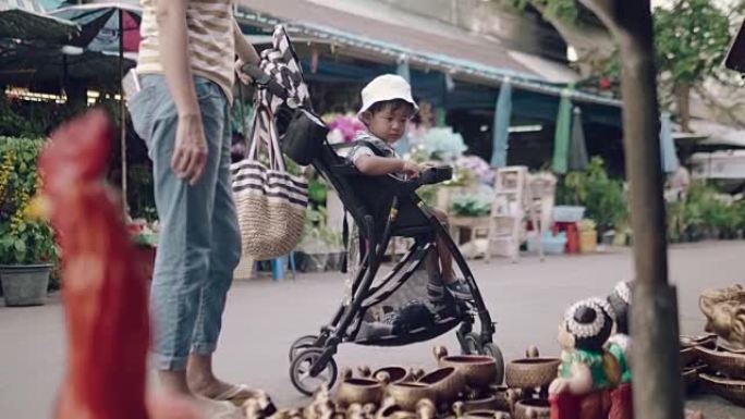 亚洲妇女和男婴在跳蚤市场购买装饰。