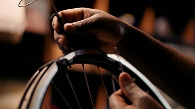 工匠的手修理自行车车轮上的辐条
