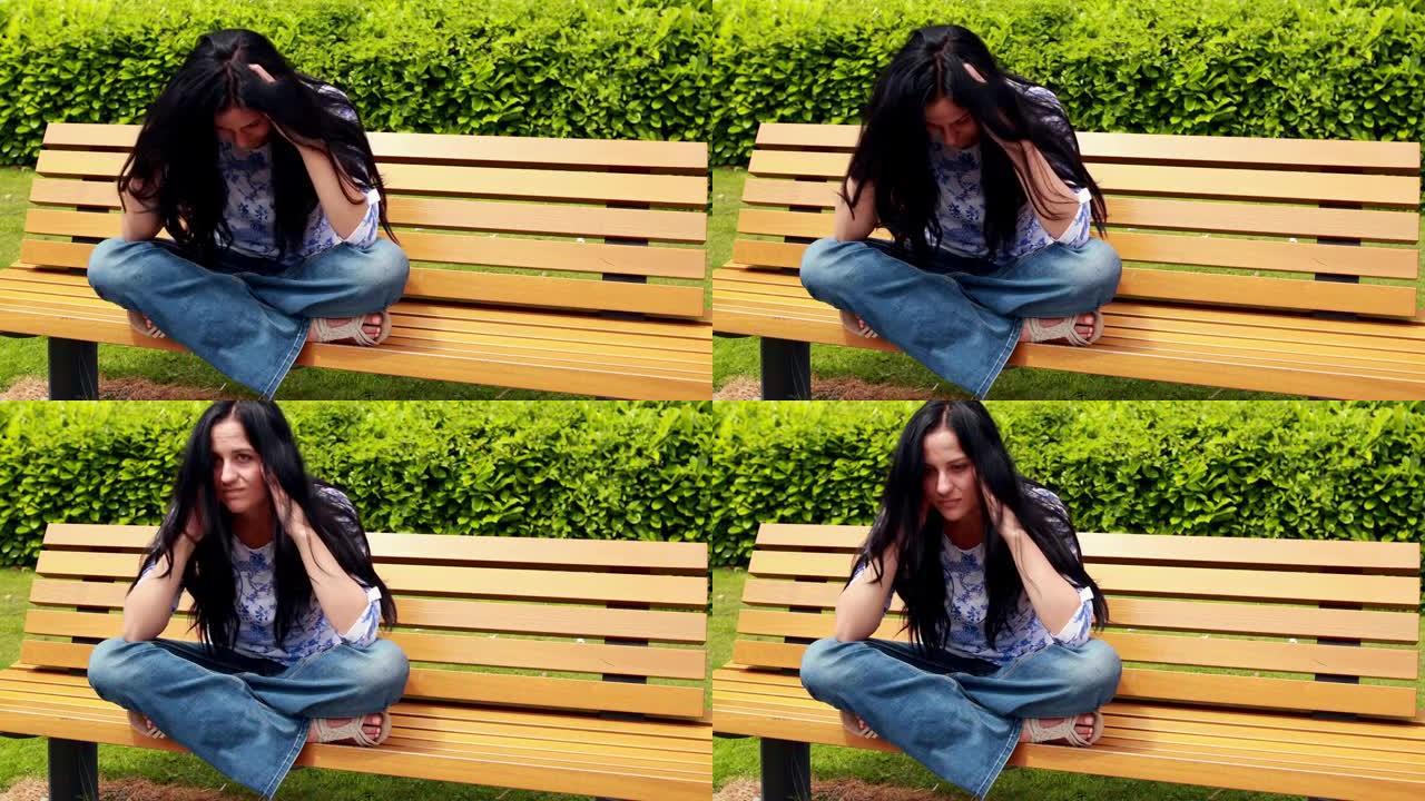 悲伤的黑发女人在公园的长凳上思考
