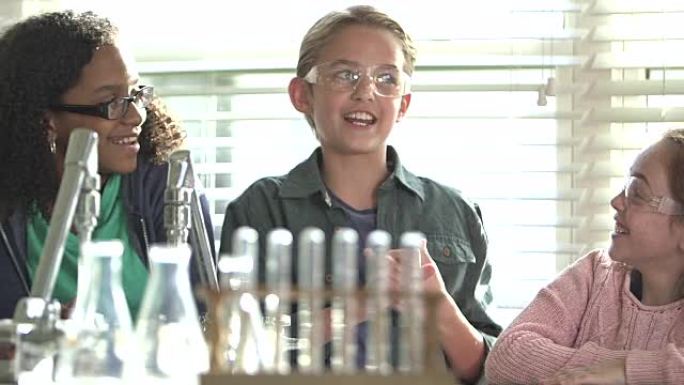 科学实验室中的三个多民族儿童，男孩在说话