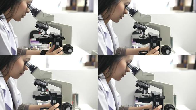 女科学家在实验室里看显微镜