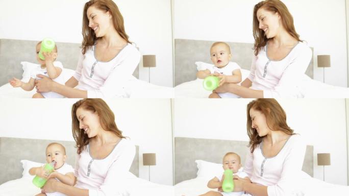 微笑的年轻母亲喂她的女婴奶瓶