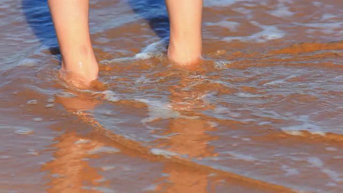 海浪在海滩上冲刷着年轻女孩的双脚