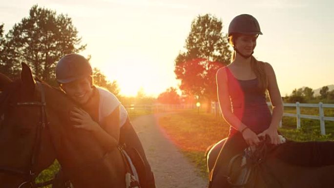 慢动作: 两个开朗的年轻女孩在神奇的日落中享受骑马的乐趣