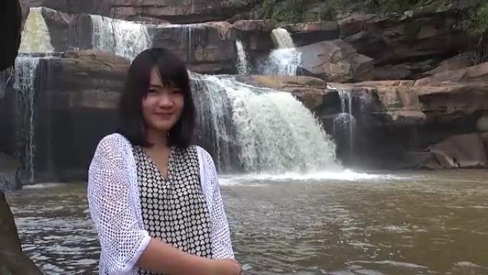 美丽的年轻女子在瀑布附近的美丽森林中放松。泰国。