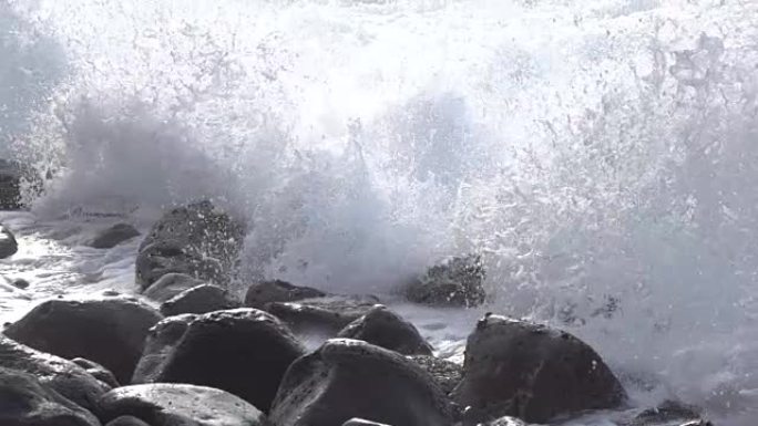 慢动作特写: 海浪撞击并溅到圆形火山岩上