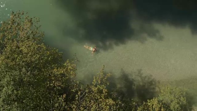 空中: 年轻女孩在旷野的绿河中游泳青蛙式技术