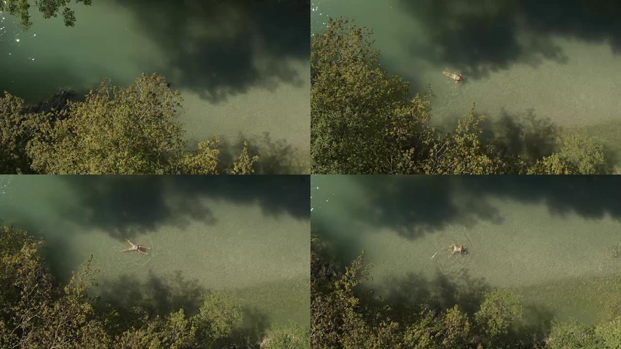 空中: 年轻女孩在旷野的绿河中游泳青蛙式技术