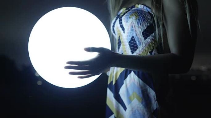 女人的手在晚上拿着发光的球灯