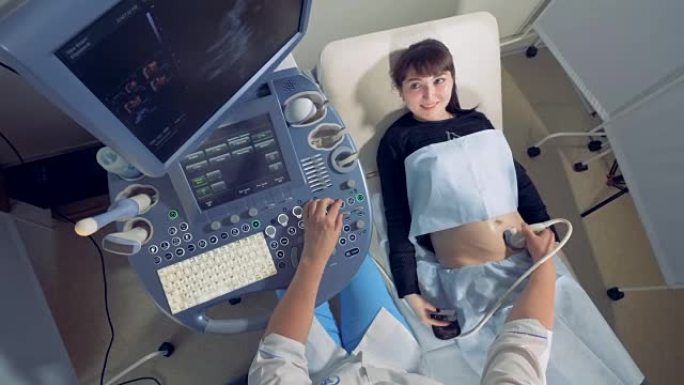 微笑的孕妇正在观察自己的超声波检查过程