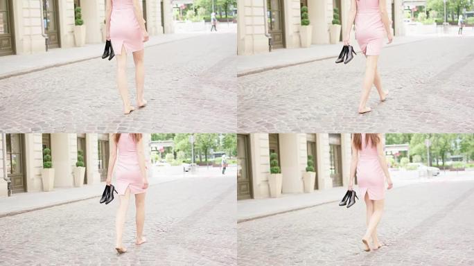 年轻的女人手里拿着高跟鞋，松了一口气。在城市中漫步