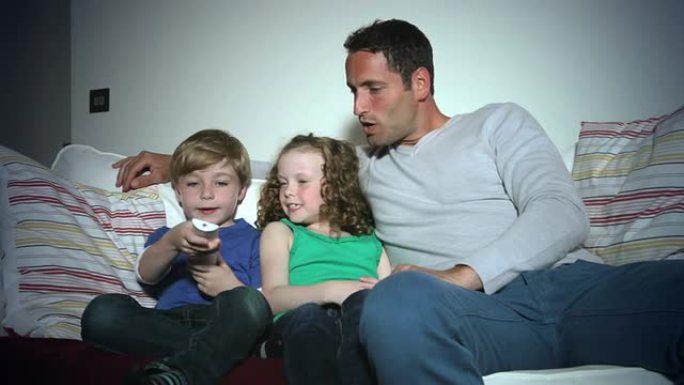父亲和孩子坐在沙发上一起看电视