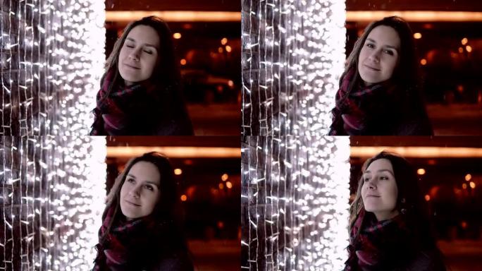 圣诞节之夜，年轻迷人的女人在飘雪中看着背景的相机灯