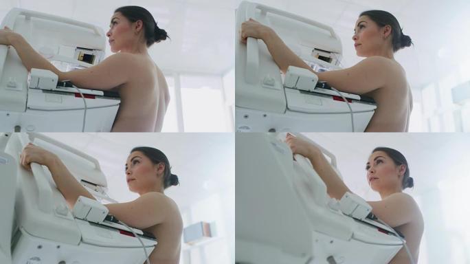 在医院，低角度肖像拍摄的半裸女性病人进行乳房x线筛查程序。健康年轻女性进行癌症预防性乳房x线摄影扫描