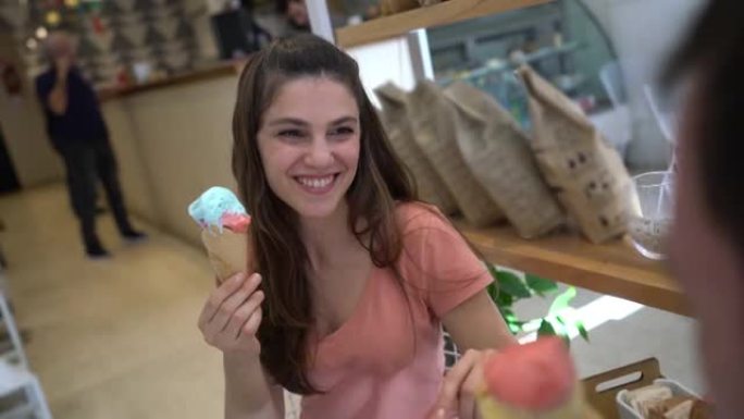 美丽的女人在冰淇淋店约会，笑着享受冰淇淋