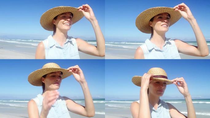 美丽的女人在海滩散步时戴着帽子