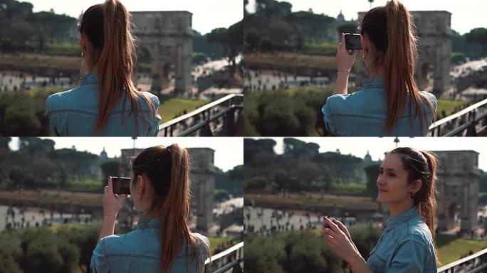 一位年轻的黑发女性游客在智能手机上微笑着拍摄了康斯坦丁拱门和意大利罗马的照片。慢动作