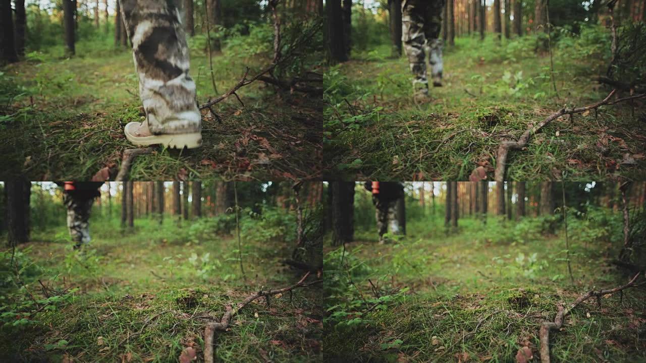 穿靴子的雄性脚的特写镜头穿过森林草地。穿着工作服的人独自探索自然公园