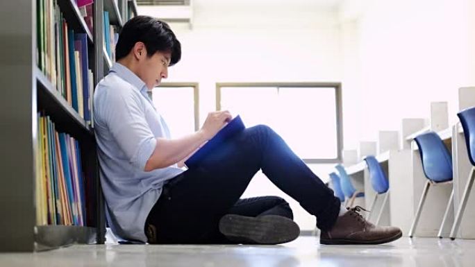 亚洲男大学生在图书馆阅读地板上进行学习研究