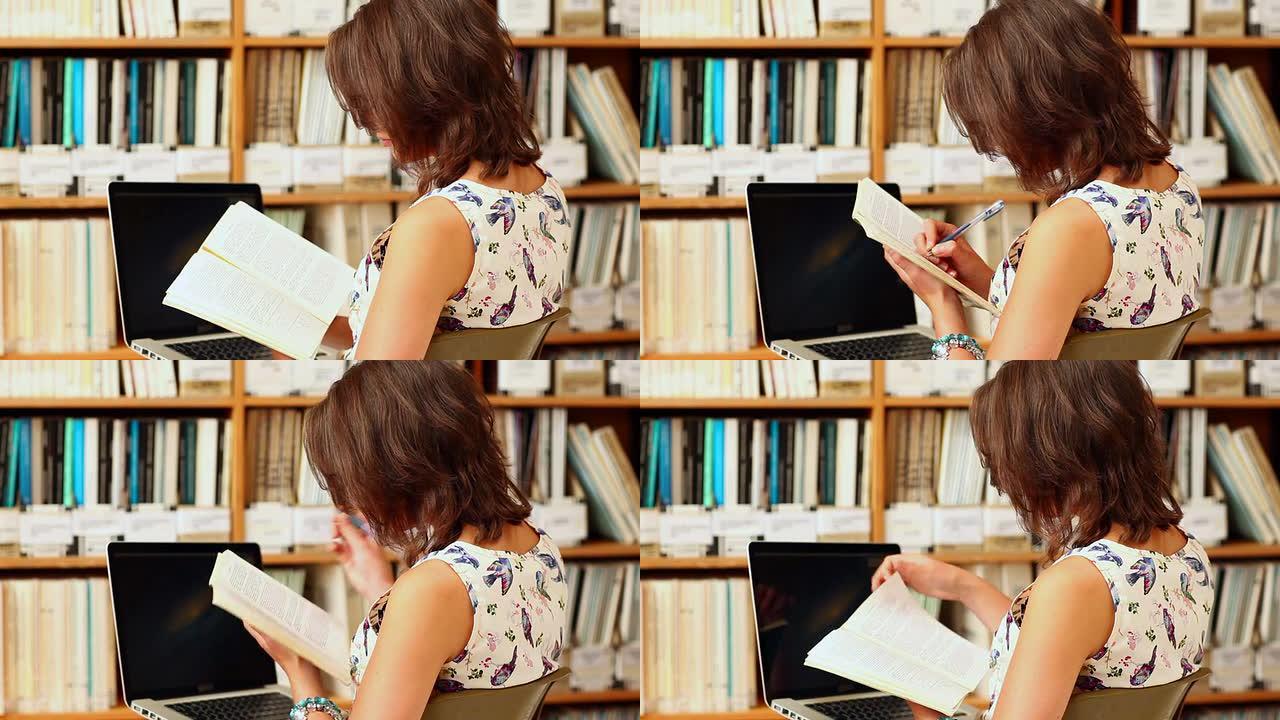 用笔记本电脑在图书馆学习的年轻女子