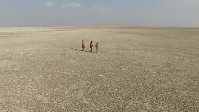 鸟瞰图，三个布希曼人走过广阔的Makgadikgadi pan，博茨瓦纳